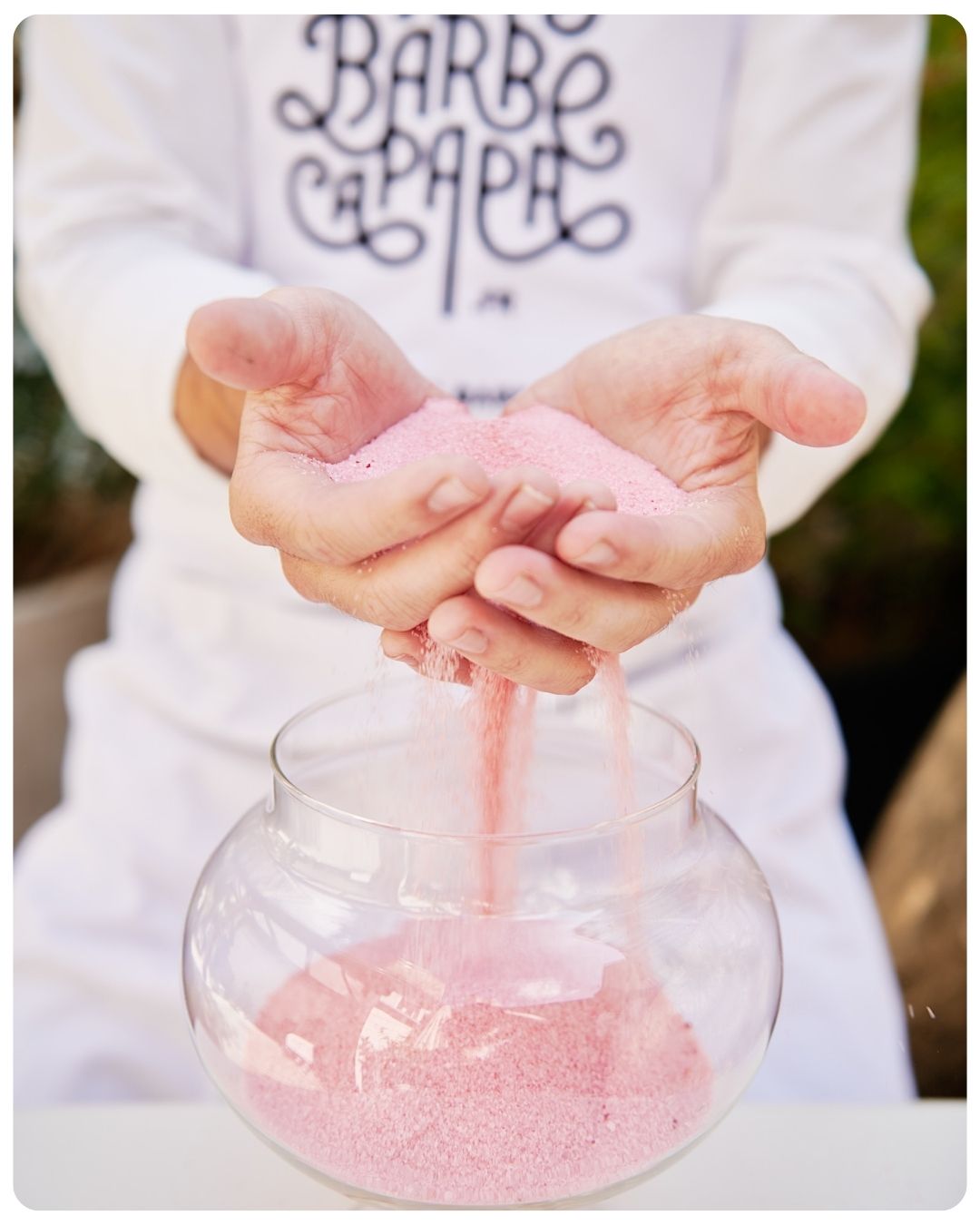 Barbista de la Maison de la Barbe à Papa laissant couler le sucre rose entre ses mains