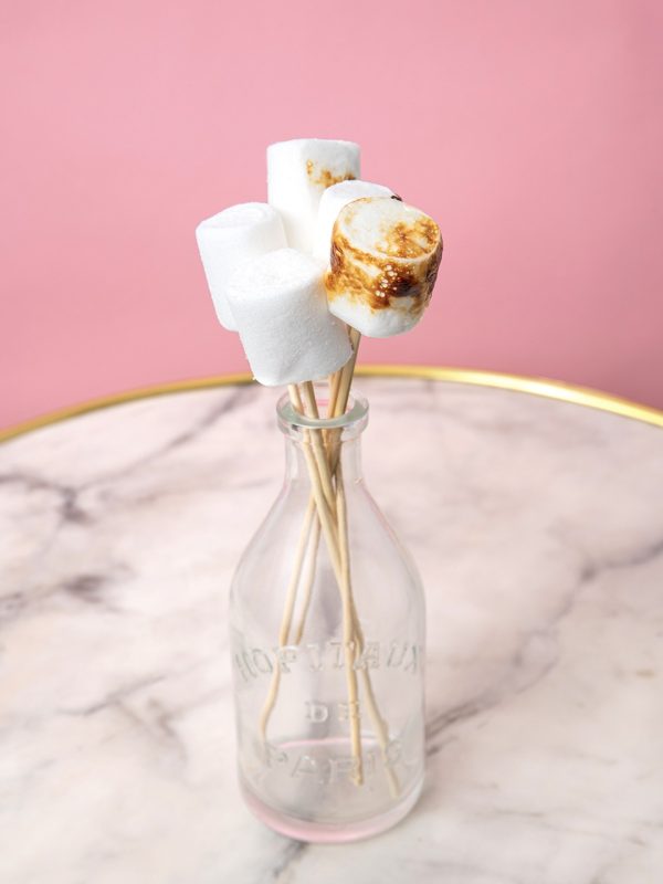 Bouteille en verre vintage servant de présentoir à brochettes de marshmallows pour animation conviviale