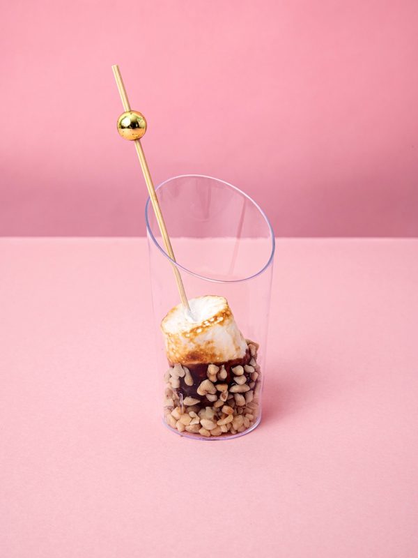 Verrine gourmande de marshmallow grillé avec toppings croquants sur fond rose pastel