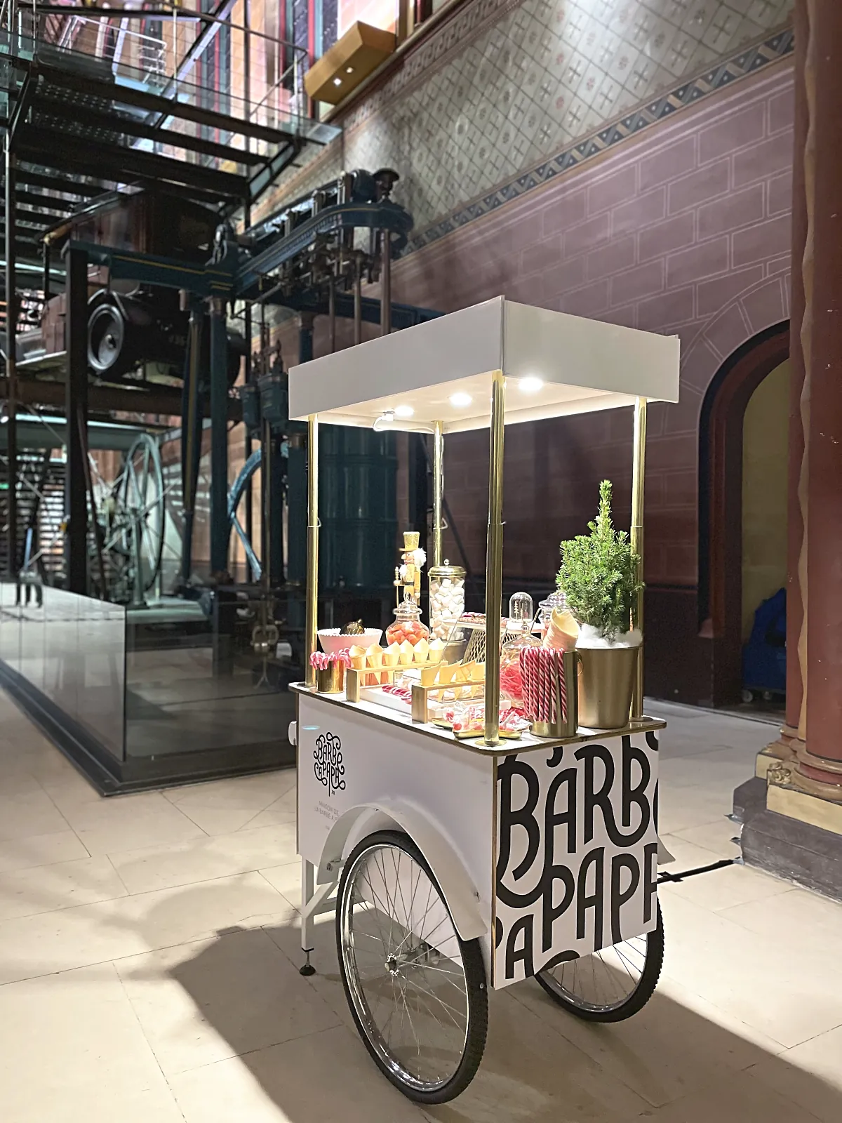 Chariot candy bar installé dans une salle de musée, devant des machines anciennes