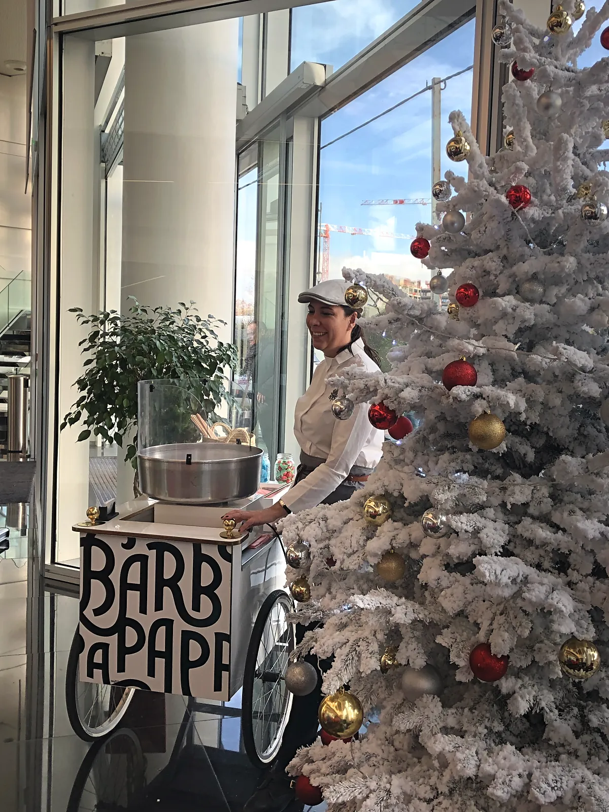 Chariot barbe à papa et animatrice devant le sapin blanc du hall vitré d'une entreprise