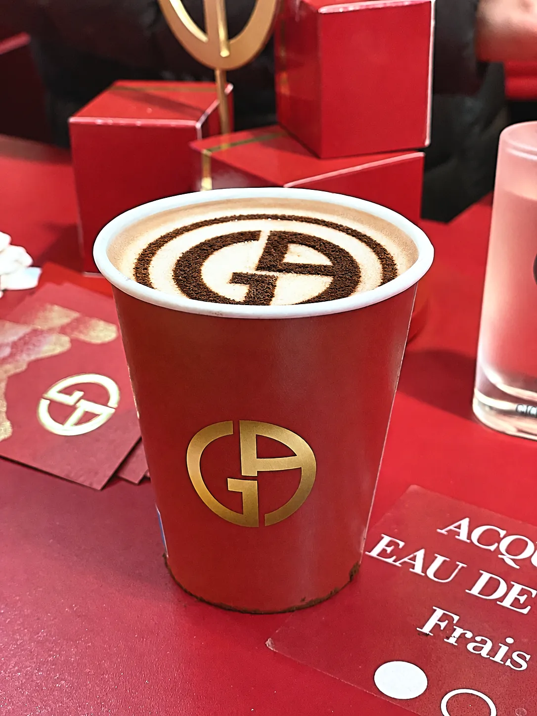 Gobelet rouge au logo doré Armani et logo dessiné au cacao sur la mousse du chocolat chaud