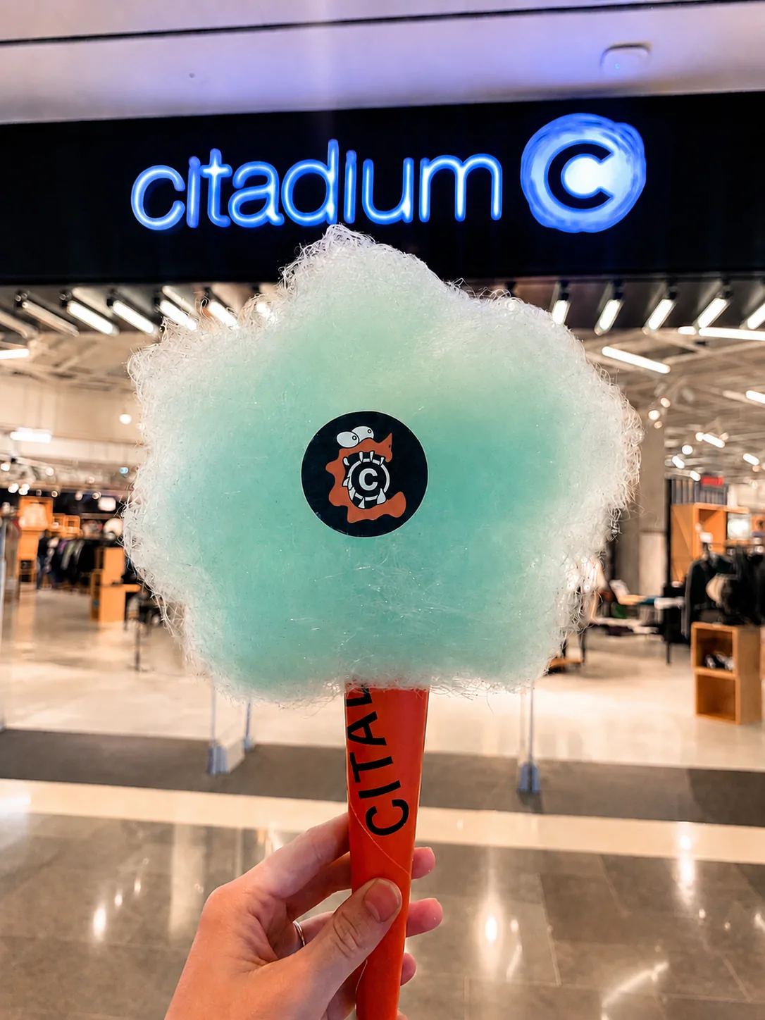 Barbe à papa d'Halloween au cornet Citadium tenue sous l'enseigne néon du magasin