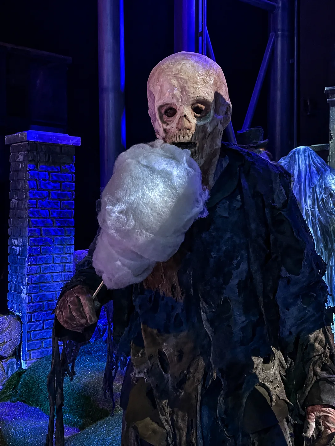 Mort-vivant avec une barbe à papa d'Halloween devant un mur de briques hanté