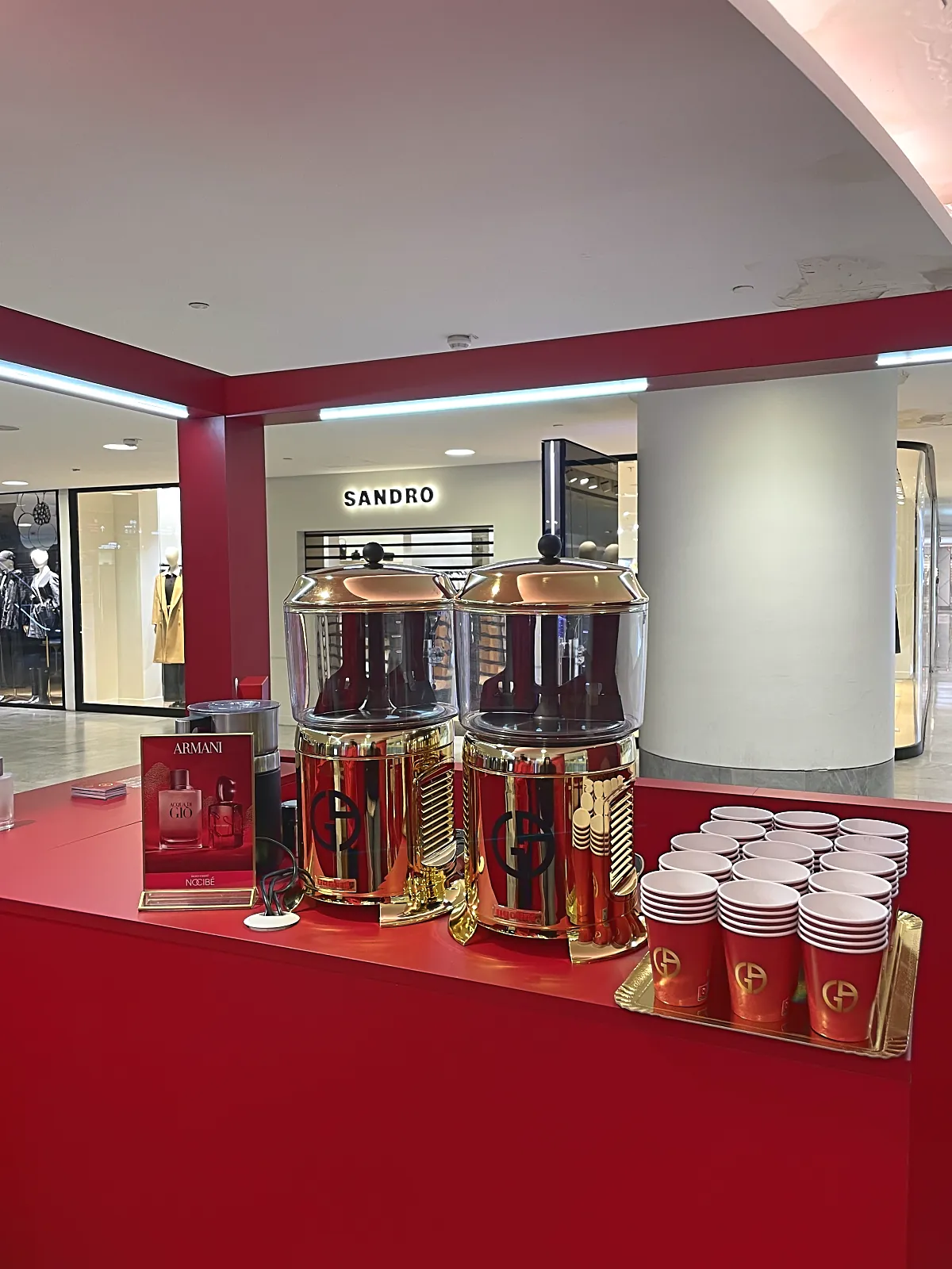 Comptoir rouge Armani avec deux chocolatières dorées et gobelets brandés au Forum des Halles