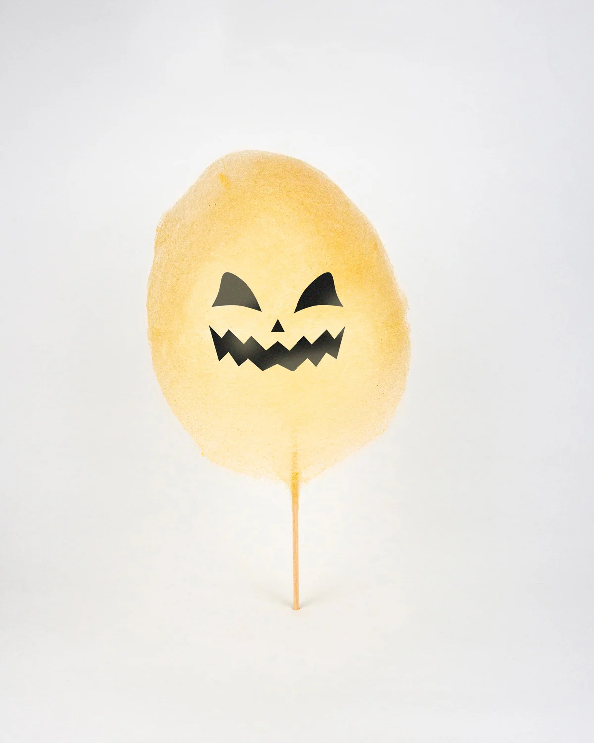 Barbe à papa d'Halloween en citrouille au visage grimaçant, yeux en amande et bouche en zigzag